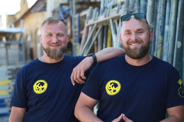 David Kaczmarek und Marek Maass von Gerüstbaufirma Berlin vor Gerüstmaterial