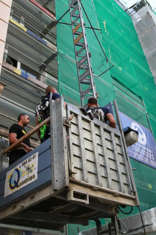 Gerüstbauer am Bauaufzug vor eingerüsteter Fassade in Berlin