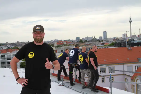 Gerüstbau-Team auf einem Dach in Berlin mit Blick zum Fernsehturm